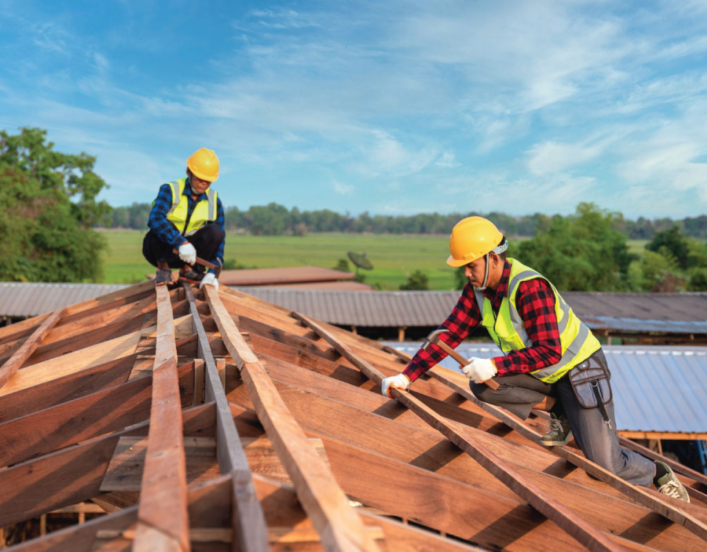 Two workers are working on roofing installation